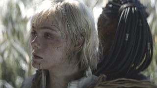 Elle Fanning as Thia looking to the side while attached to Dek in Predator: Badlands