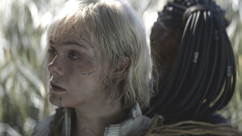 Elle Fanning as Thia looking to the side while attached to Dek in Predator: Badlands 