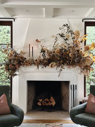 A living room with a mantel decorated with dried foliage