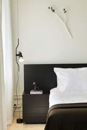 Hotel Skeppsholmen, Stockholm. A hotel bedroom with a white bed, a black side table, a black headboard and a floor lamp.