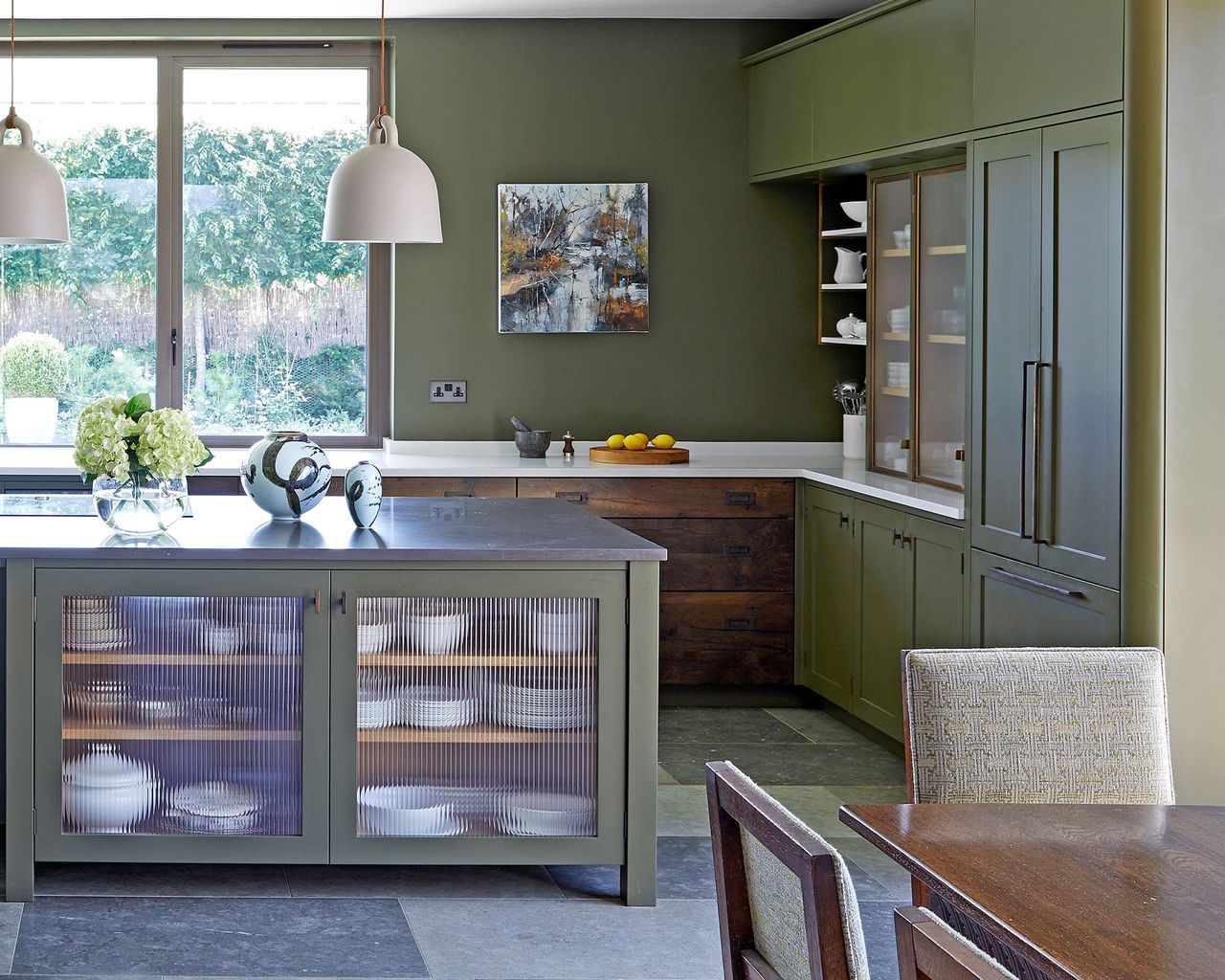 green kitchen with island and glass fronted cabinets