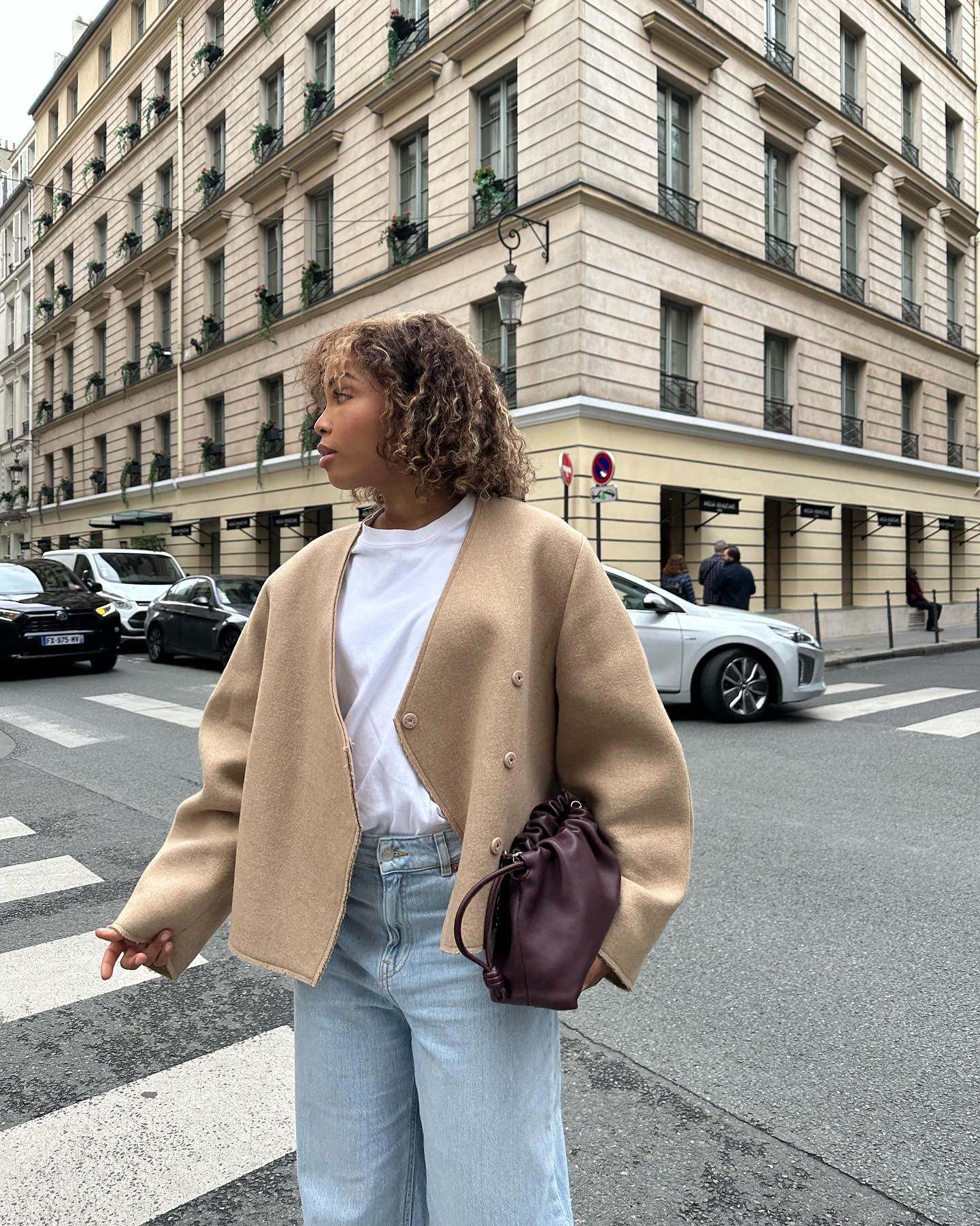 Creator @slipintostyle wearing an autumnal jacket with curly hair and blonde highlights