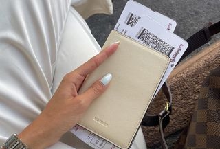 woman holding cream-colored passport holder