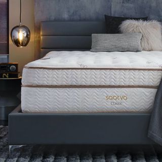 Lifestyle image of the Saatva classic mattress, blue bedroom with wooden bedside table