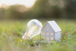 paper house with a lightbulb in a grassy field