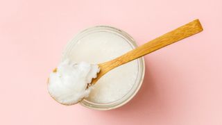 spoon of coconut oil on pink background