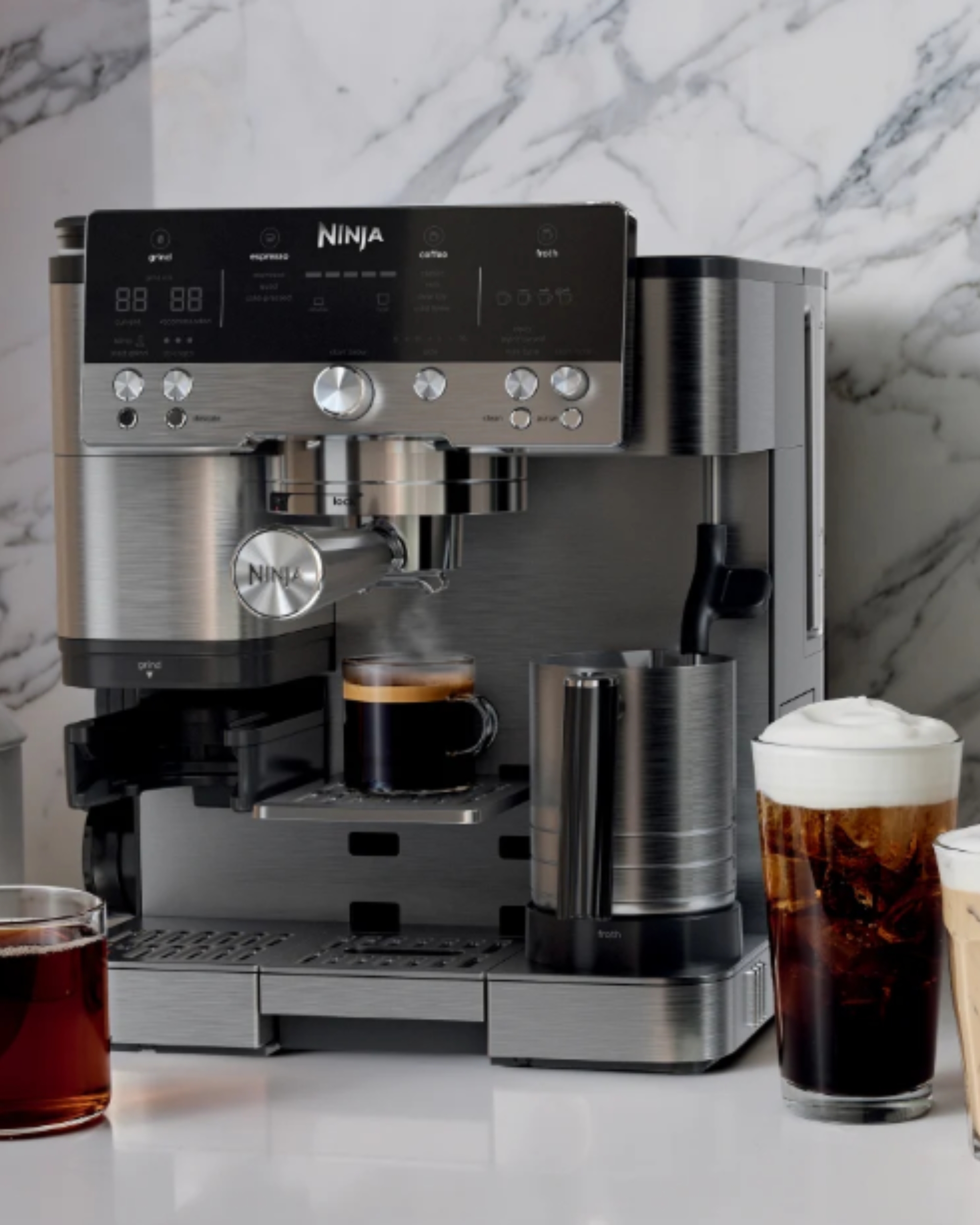 Close-up image of a ninja espresso machine making an espresso shot with multiple other coffee drinks placed in front of it.