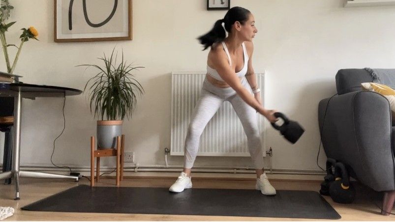 Writer Sam swinging kettlebell across her body during lateral kettlebell swing