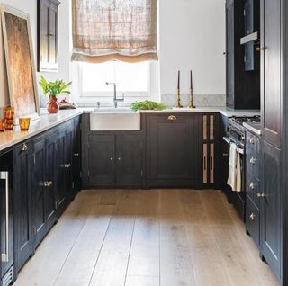 kitchen with matt black wall cabinet and marble worktop with rustic timber floor