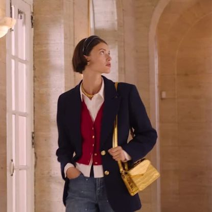woman with a navy blue blazer, red vest, and yellow handbag