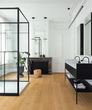 natural oak wood effect flooring in bathroom with high ceilings, black and grey modern vanity unit and a black framed walk in shower enclosure