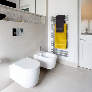 white bathroom with steel towel rack and toilet
