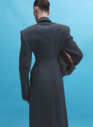Model with back to camera in cinched waist grey overcoat