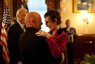 Captain Mark Kelly hugs his wife Congresswoman Gabrielle Giffords after receiving the Legion of Merit from Vice President Joe Biden during Captain Kelly's retirement ceremony in the Secretary of War Suite in the Eisenhower Executive Office Building, in Washington, D.C., Oct. 6, 2011.