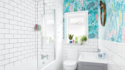 Small white bathroom with wooden floating vanity unit and large round mirror on wall 