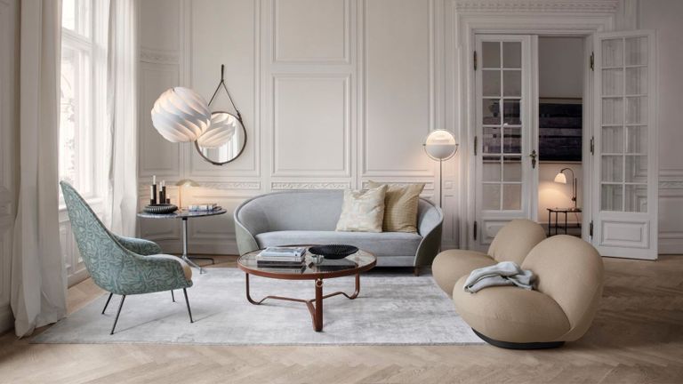 The Gubi Pacha accent chairs in a high-ceilinged living room with decorative panelling