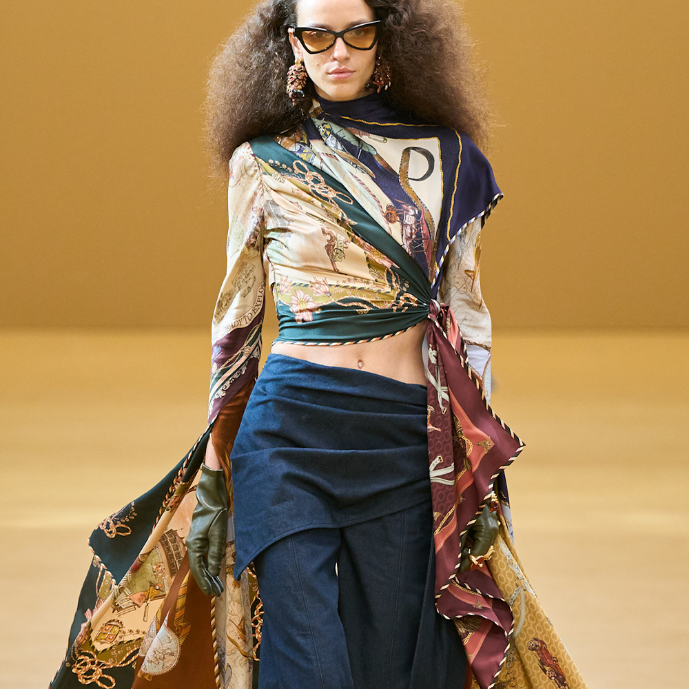 A model wearing hybrid jeans with a patterned silk cape top and sunglasses on the Zimmermann A/W 2026 runways 