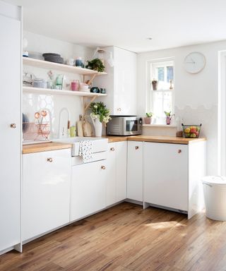 kitchen with white wall and wooden floor and white cabinet with wooden worktop