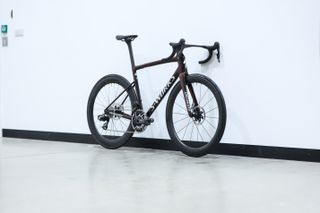 A red Specialized S-Works Tarmac SL8 stands against a white wall