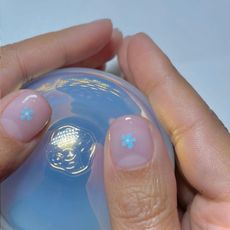 A photo featuring Harriet Westmoreland's milky manicure and blue flower nail art