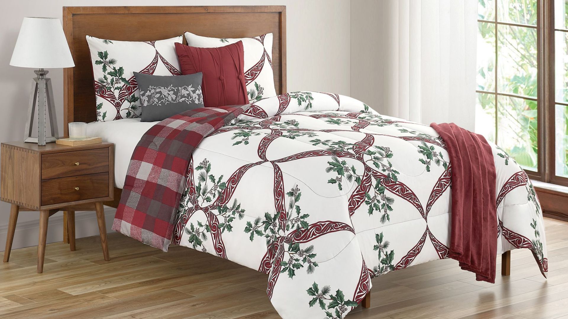 A white Christmas bedding comforter set with red ribbon designs and holly leaves that reverses to a red and gray plaid design.