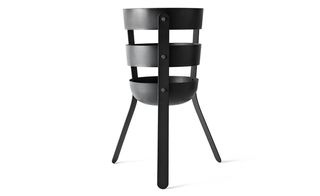 Fire bucket, by Norm for Menu. A fire holder made from black metal rounded bars and three legs.