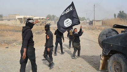 Iraqi government forces hold an Islamic State flag after they claimed they controlled an Islamic State town