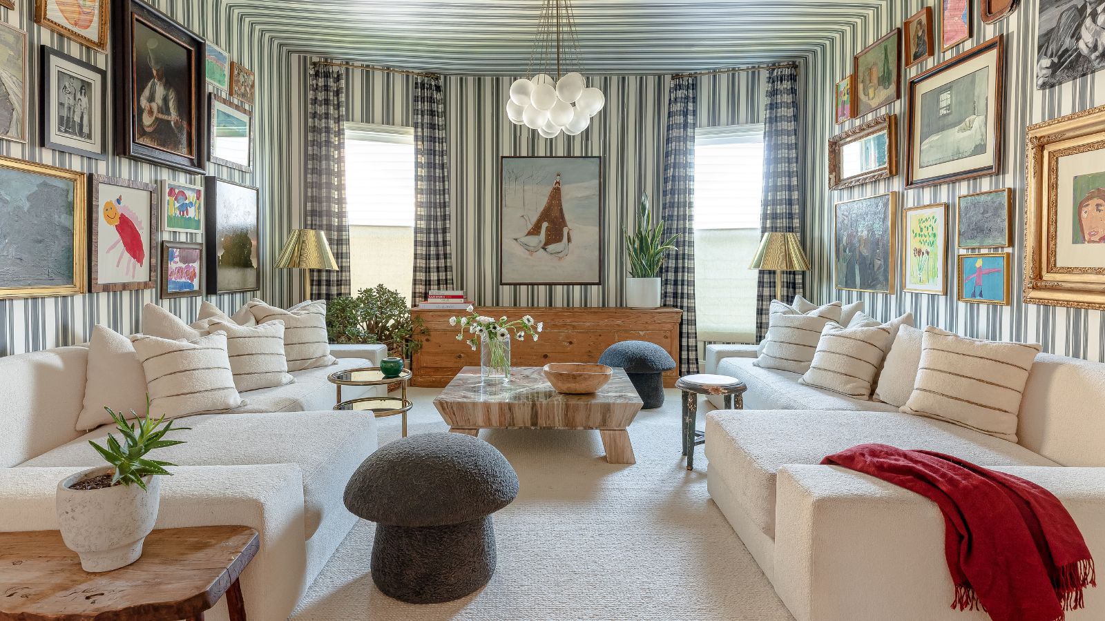 maximalist living room pattern drenched in striped wallpaper on the walls and ceiling, gingham curtains, two vintage gallery walls on opposite sides and two matching white corner sofas with a mushroom ottoman stool