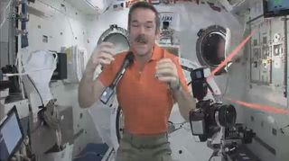 Astronaut Chris Hadfield aboard the International Space Station speaks with a Canadian Space Agency colleague on Feb. 7, 2013, while his microphone and camera float nearby in zero-g.