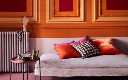Purple sofa in a orange and dark red painted room