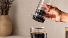 A clear AeroPress over a clear cup of coffee