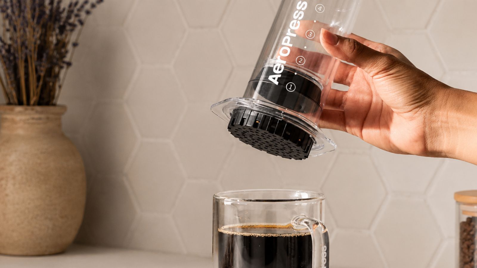 A clear AeroPress over a clear cup of coffee