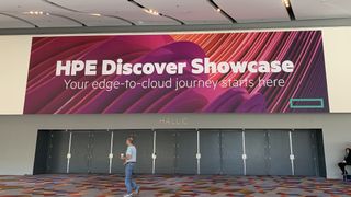 A sign reading HPE Discover Showcase above some closed doors with a man walking past