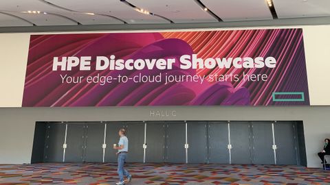 A sign reading HPE Discover Showcase above some closed doors with a man walking past