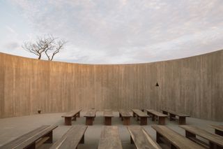 minimalist spiritual enclosure structure in pink hue concrete among desert green nature