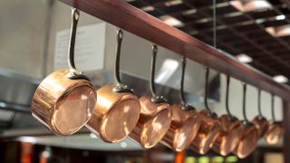 Copper pots hanging under shelf