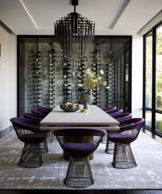 Dining room with feature wall of wine racks and purple velvet dining chairs