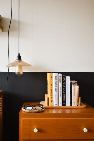 A dresser table with a stack of books and a pendant light hanging from overhead