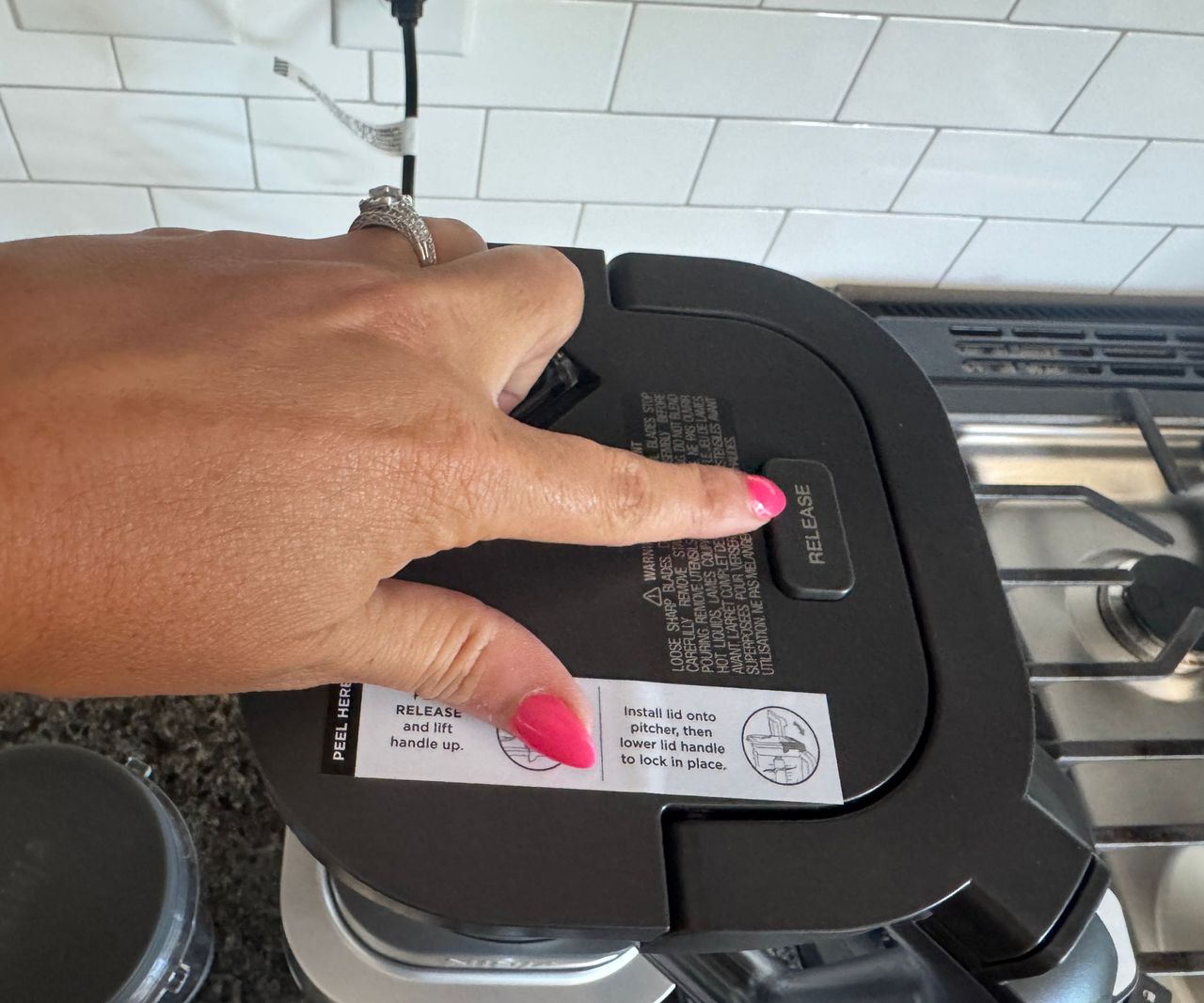 A close up of pressing the release button on the top of the Ninja Foodi Power Blender Ultimate System