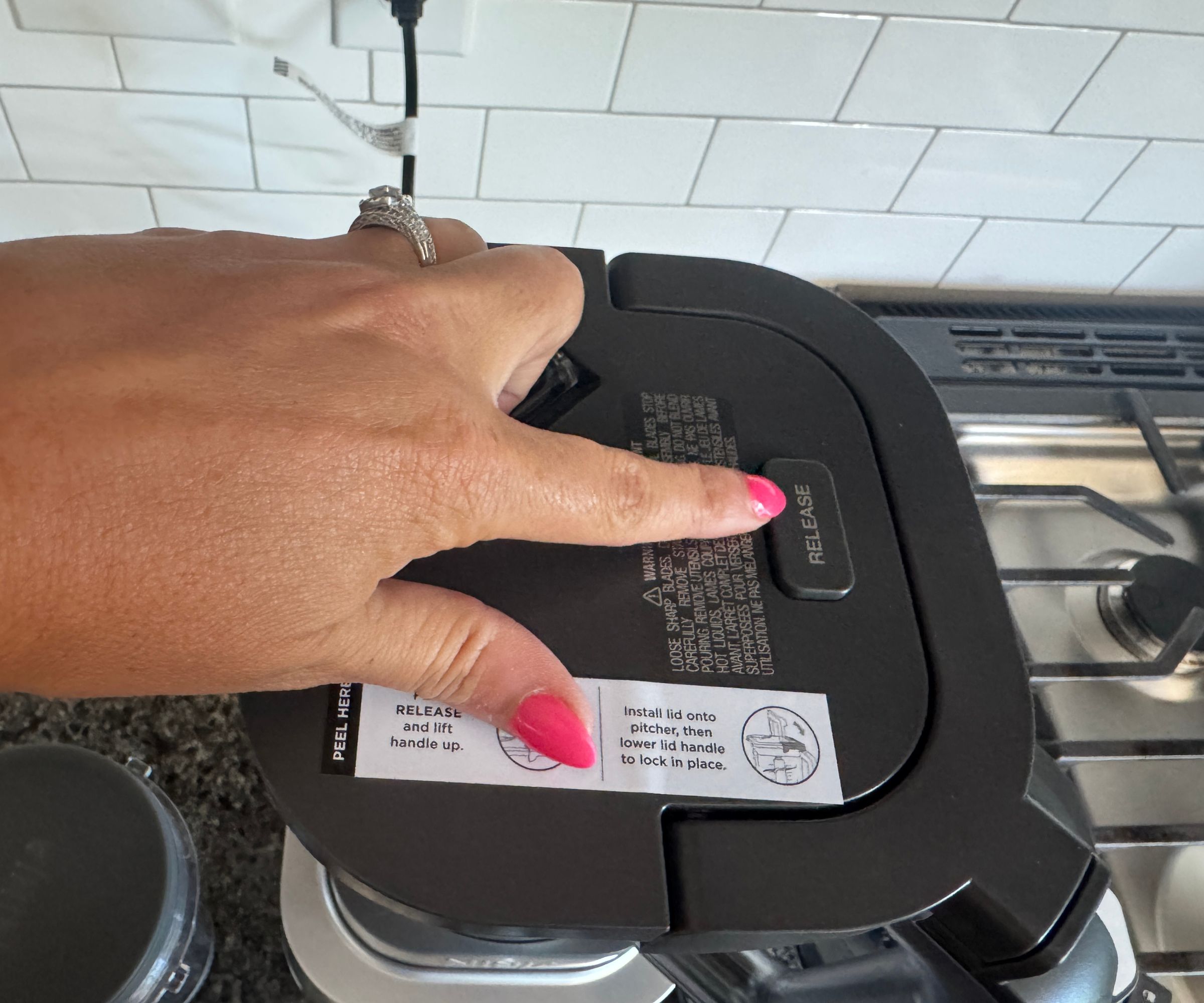 A close up of pressing the release button on the top of the Ninja Foodi Power Blender Ultimate System
