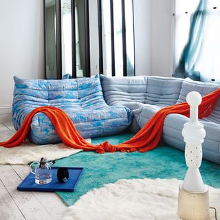 room with blue sofa and faux fur rug and wooden floor and throw