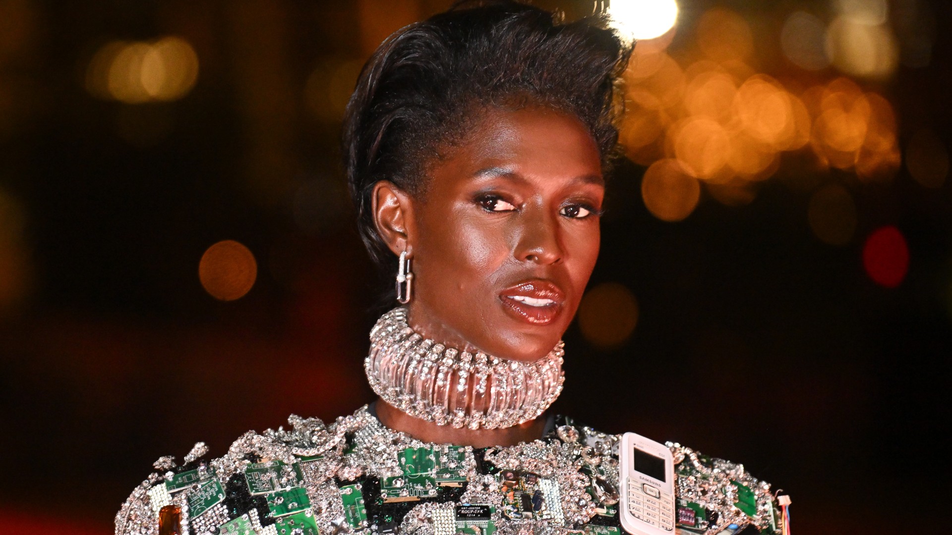 a black woman with short, black hair poses during a runway show