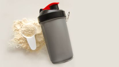 protein powdet shaker with a scoop of protein next to it
