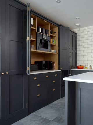 kitchen with dark coloured cabinets and larder by Higham Furniture