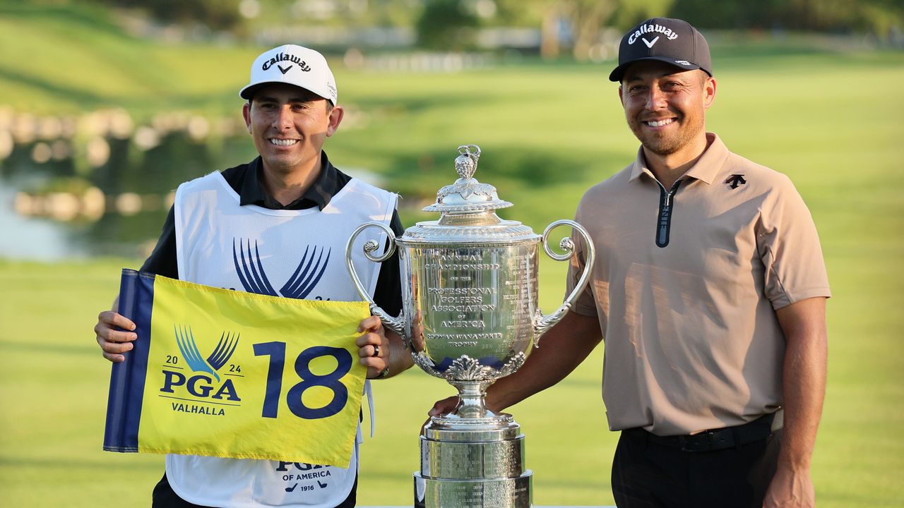 Austin Kaiser holds up a PGA Championship flag next to the Wanamaker Trophy and Xander Schauffele