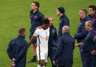 Marcus Rashford is consoled by the England coaching staff after missing a penalty against Italy in the final of Euro 2020.