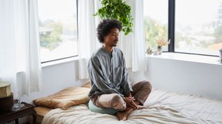 Young man doing yoga in bed