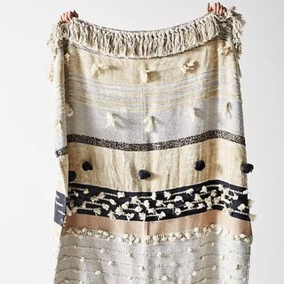 Textured, neutral throw with fringing and tassels