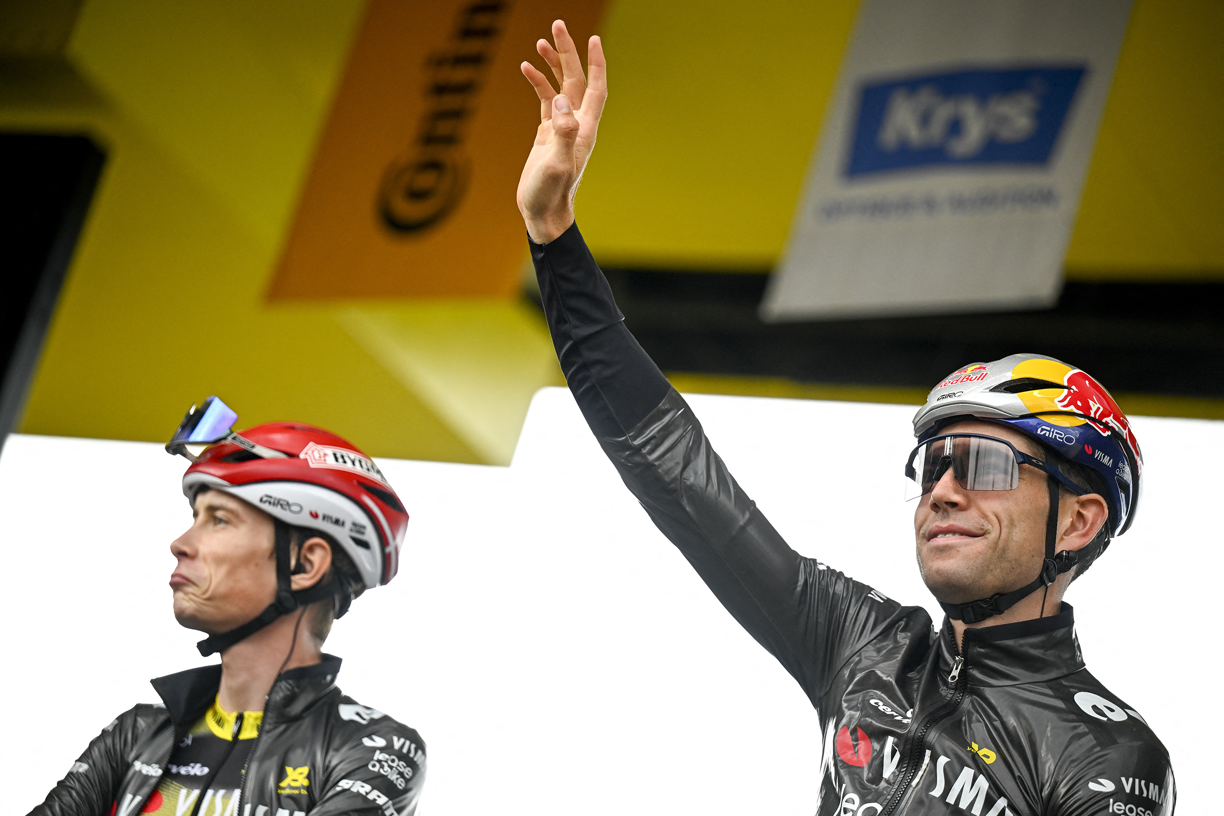 Wout van Aert waves to the crowd from stage of Tour de France presentation, Jonas Vingegaard is next to him