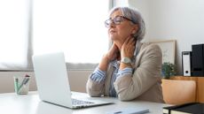 woman at desk hold neck in pain